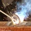 A skilled welder working on a metal fabrication, wearing protective gear and joining metal pieces together.