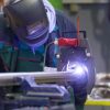 An industrial operator configuring the computer-controlled orbital welding machine for stainless steel pipe fabrication.