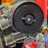 An automated pipe spool machine is affixed to a large metal pipe, with its intricate arrangement of parts and wiring.