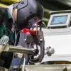 An industrial worker wearing a welder's helmet inspects an orbital welding machine to manufacture a precise weld.